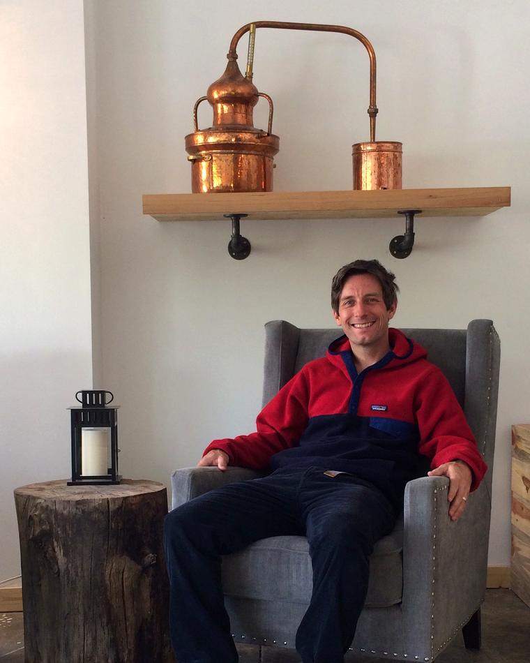 Ryan Max Riley beside the miniature copper pot still used to work out recipes